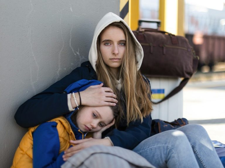 zur Seite: JUGENDLICHE Sechs Jugendliche sitzen auf einer Mauer am Meer, während die Sonne untergeht.